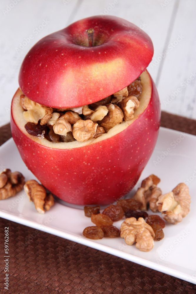 Apples with raisins and nuts on plate on table close up