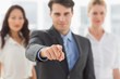 © WavebreakMediaMicro - Smiling businessman pointing to camera in front of his team