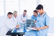 © WavebreakMediaMicro - Female surgeon looking at reports with colleagues in meeting