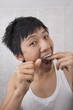 © MDBPIXS - Portrait of mid adult man flossing his teeth in bathroom