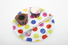 Cupcakes And Fork In Multicolored Plate Against White Background