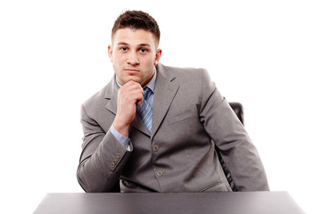 Pensive businessman sitting at the table with hand on chin