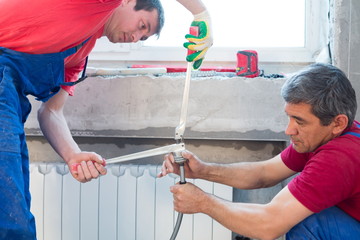 Workers prepare pipes for heating system crimping