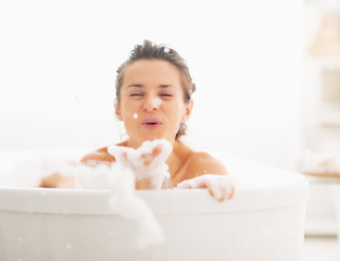 Wall Mural - Happy young woman playing with foam in bathtub