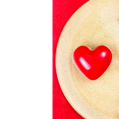 Red Heart on golden plate on red tablecloth isolated on white ba