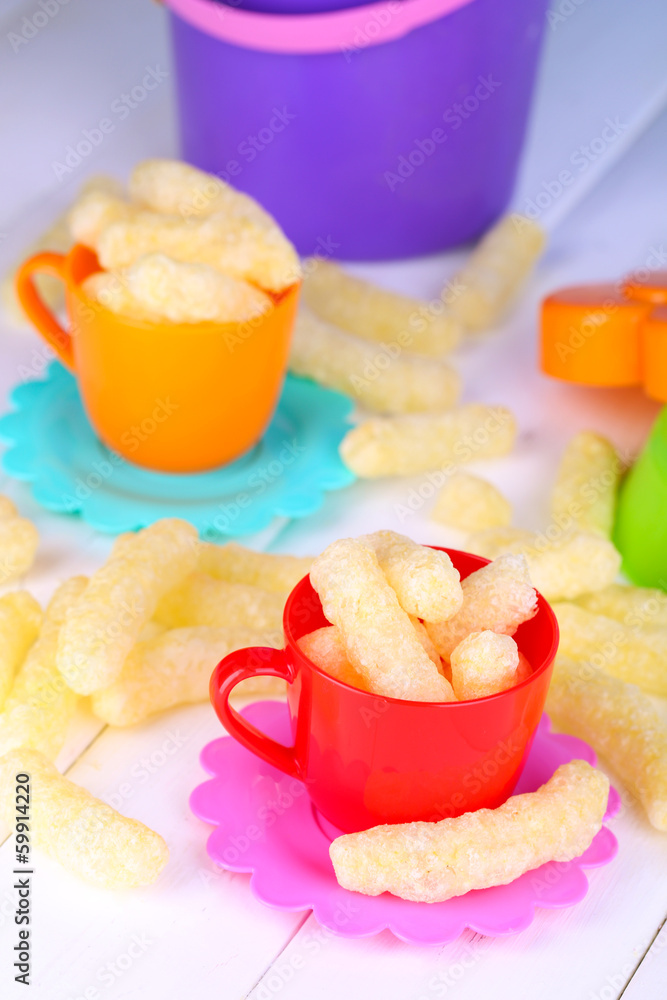 Corn sticks in children toy dishes on wooden table close-up