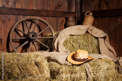 Obraz w ramie Interior of a rural farm - hay, wheel, cowboy hat.