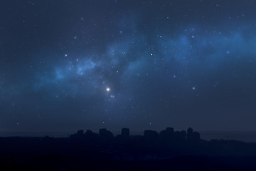 Wall Mural - city landscape at night with star filled sky, nebula and galaxy