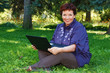 © seniorcarlo - Woman with laptop on green lawn.