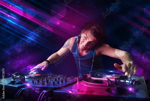 Plakat na papierze fotorealistycznym Młody dj grający na gramofonach z kolorowymi efektami świetlnymi