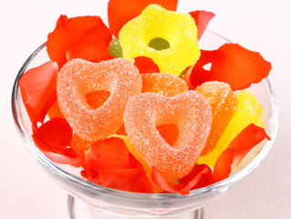 Colored candies with two red hearts in rose petals