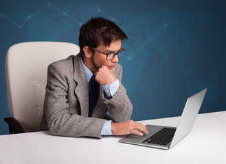 Young man sitting at desk and typing on laptop