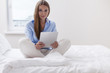 © MDBPIXS - Beautiful woman using tablet computer on her bed