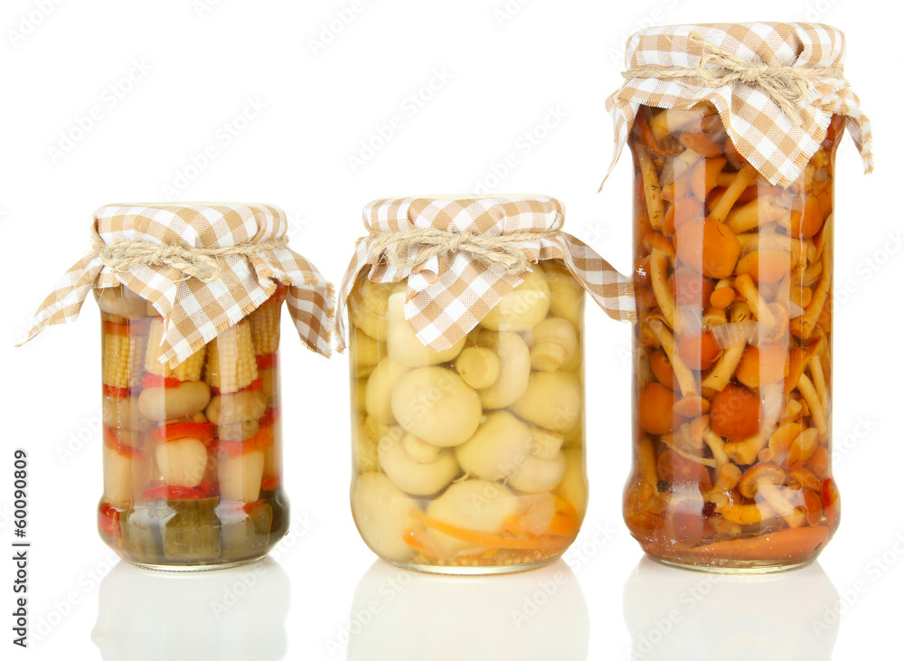 Delicious marinated mushrooms in glass jars, isolated on white