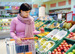 pretty woman choosing apple at fruit supermarket