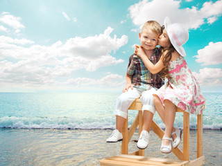 little girl kissing boy on sea landscape at sunset