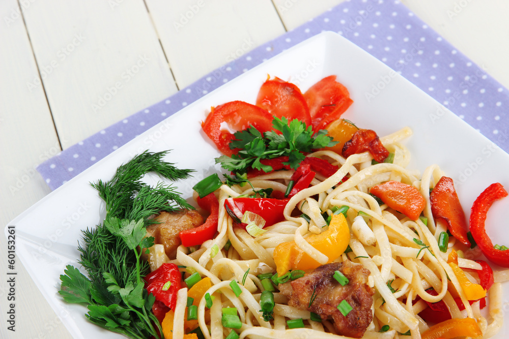 Noodles with vegetables on plate on wooden table
