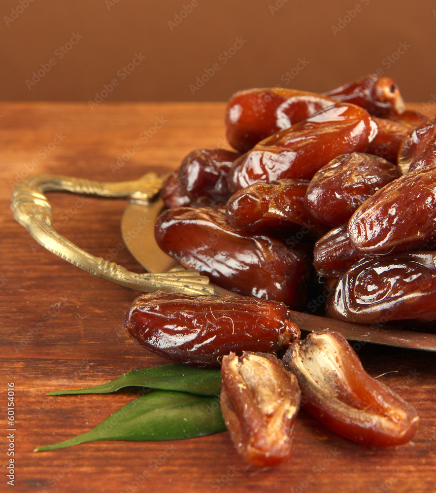 Dried dates on metal tray on wooden background