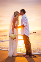 Wall Mural - Married couple, bride and groom, kissing at sunset on beautiful