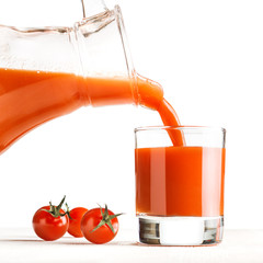 Tomato juice pouring from jug into a glass