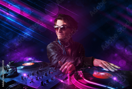 Plakat na papierze fotorealistycznym Młody dj grający na gramofonach z kolorowymi efektami świetlnymi