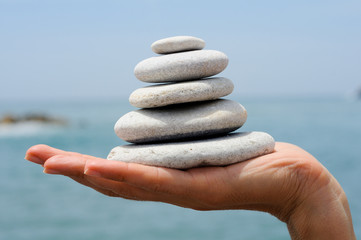 Gravel pile in woman's hands with sea background