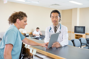 Doctor And Nurse Using Digital Tablet At Hospital Reception