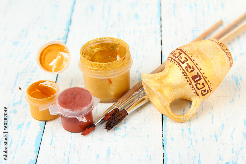 Hand made ceramic amphora and color paints on wooden table