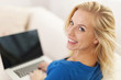 © gpointstudio - Blonde woman sitting at home with laptop