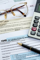 Tax form with pen, calculator, and glasses taxation concept