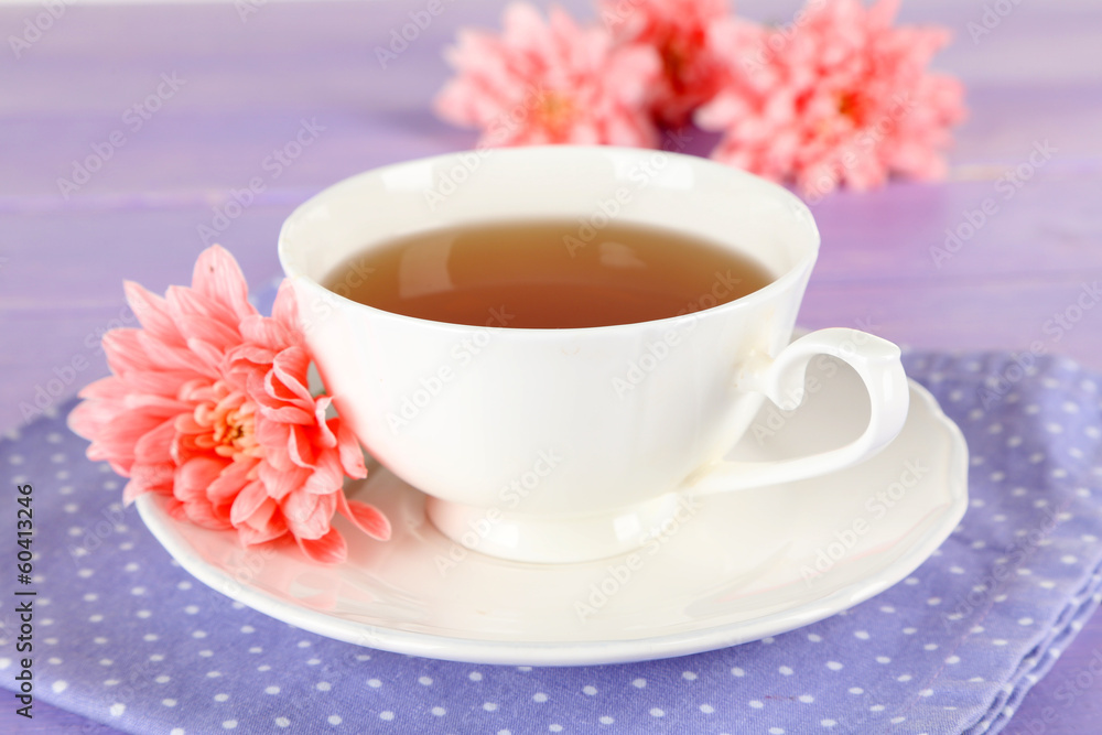 Pink chrysanthemums and cup of tea on wooden table