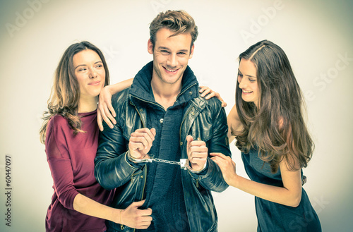 Cuadros en Lienzo Modern threesome Love - Two women with handcuffed Man