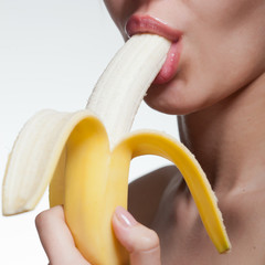 Young woman biting banana isolated on white