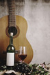 Still life of red wine bottle and wine glass with acoustic guita