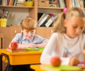 Fototapete - Children behind school desks during lesson