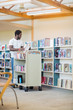 © Tyler Olson - Librarian With Trolley Arranging Books In Library
