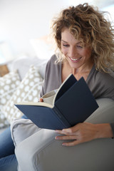 Woman reading book at home in sofa