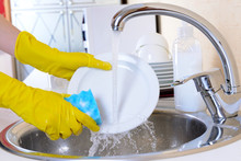 Close Up Hands Of Woman Washing Dishes In Kitchen