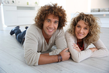 Wall Mural - Cheerful couple laying down on wooden floor