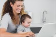 © WavebreakmediaMicro - Smiling woman with baby using laptop
