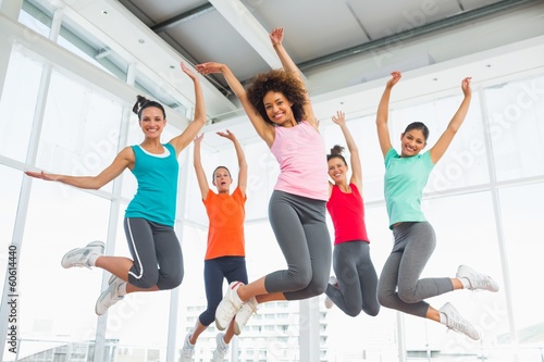 Naklejka ścienna Fitness class and instructor jumping in fitness studio