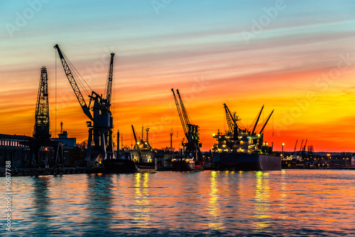 Board z aluminiowym obramowaniem Port w gdańsku podczas pomarańczowego zachodu słońca.