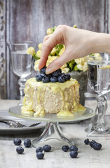 Wall Mural - Woman decorating layer cake with ripe blueberries