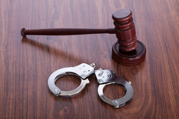 Gavel And Handcuffs On Wooden Table