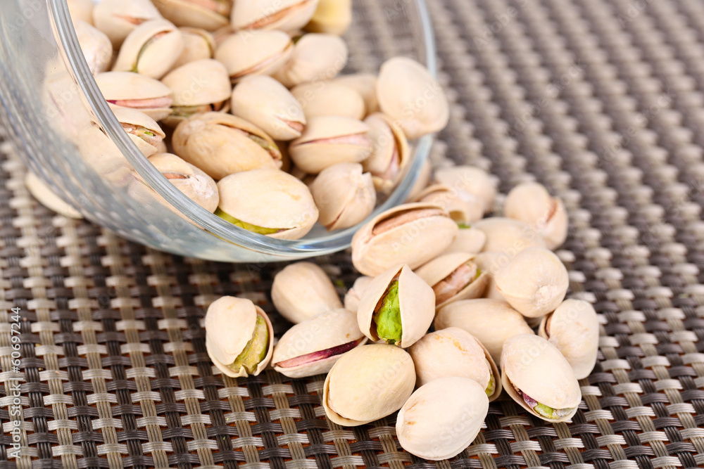 Pistachio nuts in glass bowl on table close up