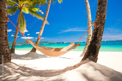 Valokuva Straw hammock in the shadow of palm on tropical beach by sea