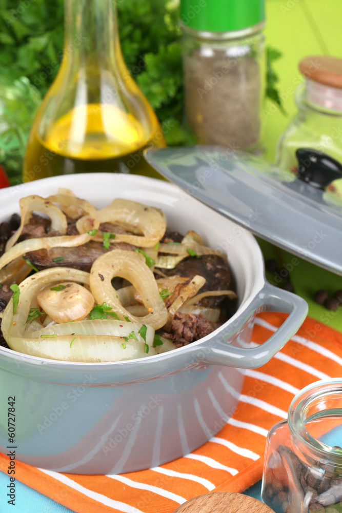 Fried chicken livers in pan on wooden table close-up