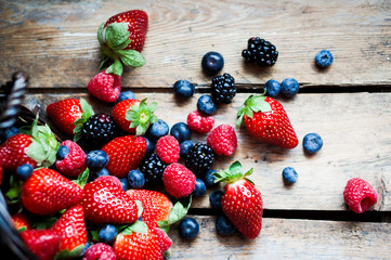 Wall Mural - Mix of fresh berries in a basket on rustic wooden background