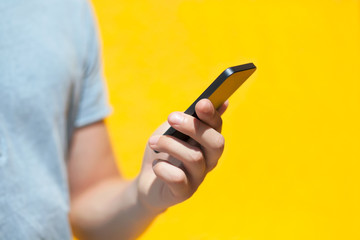 boy holding a touch phone against a yellow wall