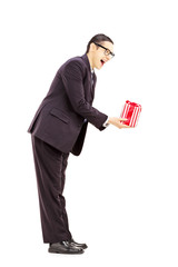 Wall Mural - Full length portrait of excited young man suit giving a gift